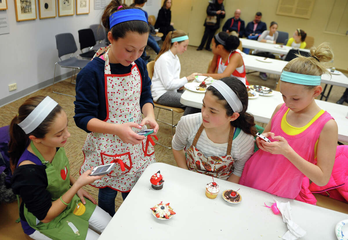 Ella Franzese, 11, left, and her friends Roxy Augeri, 11, Caroline Vandis, 11, and Annie Bowens, 11, at right, snap pictures of their desert creations after taking part in Westport READS: Teen Master Chef competition in the McManus Room at the Westport Library in Westport, Conn. on Saturday January 18, 2014. The kids got to create their own desert and compete for best cupcake, best use of ingrediants, and best presentation. The event ties in with the Westport READ program's highlighting the life and work of master chef Julia Child.