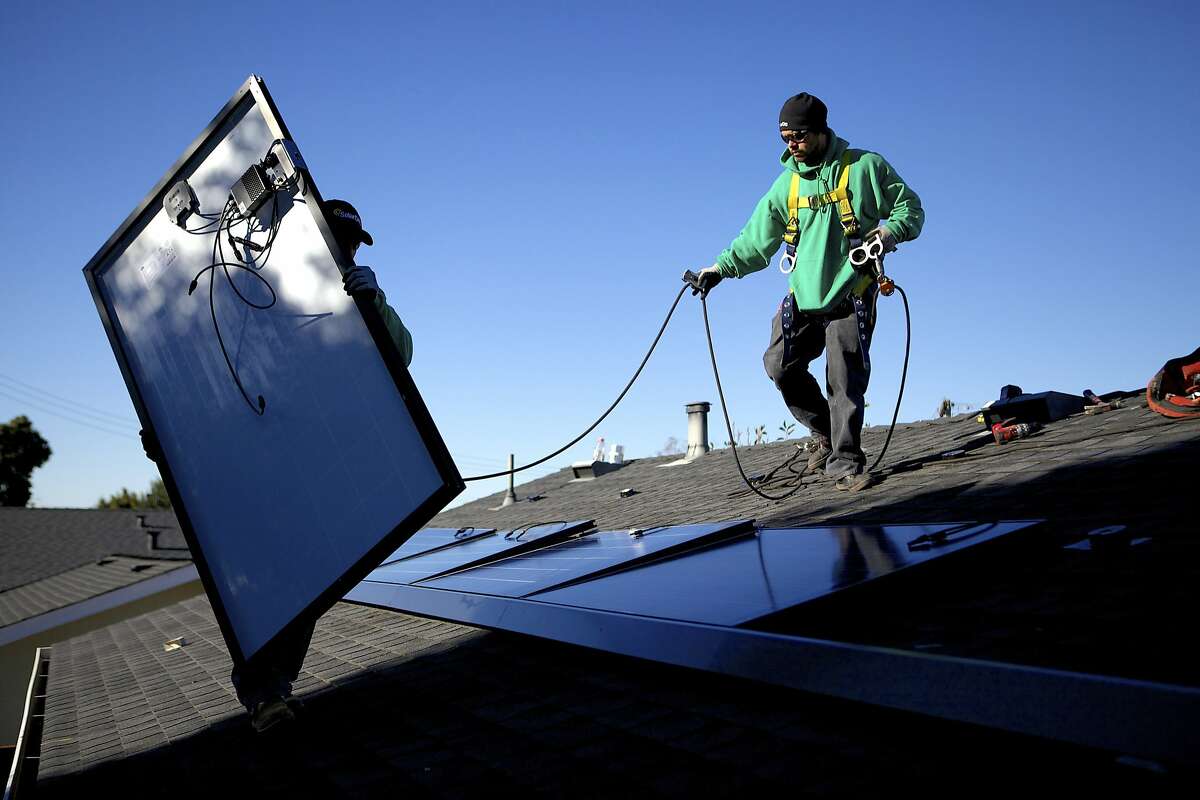 SolarCity employees Luis Zavala, left, and Jose Gazo install photovoltaic panels on the roof of a house in San Leandro, Calif., Dec. 9, 2013. The company, which is the nationâ€™s largest provider of rooftop solar energy with more than 80,000 customers, has not made a dime but its share price has soared more than 500 percent in the past year. (Thor Swift/The New York Times)