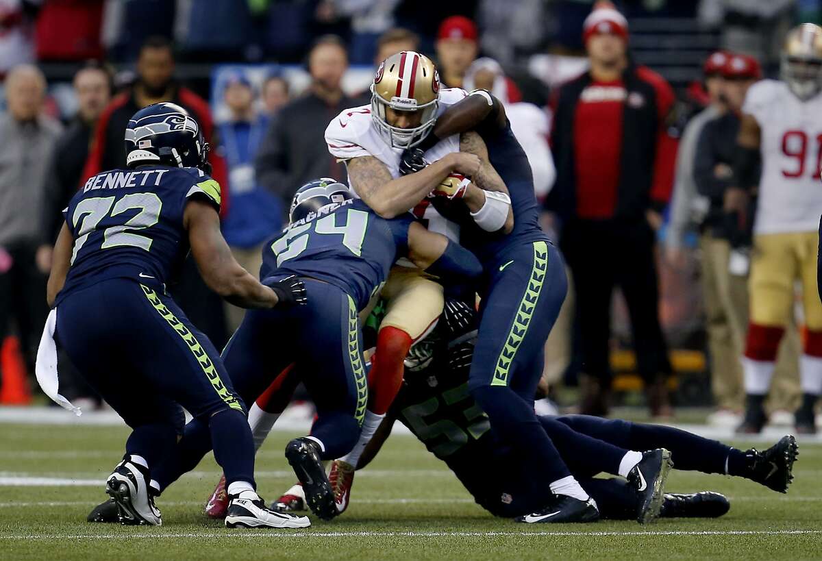Colin Kaepernick (7) was tackled by a group of Seahawks in the first half Sunday January 19, 2014. The Seattle Seahawks defeated the San Francisco 49ers 23-17 to win the NFC championship and a trip to the Super Bowl at CenturyLink Field in Seattle, Washington.