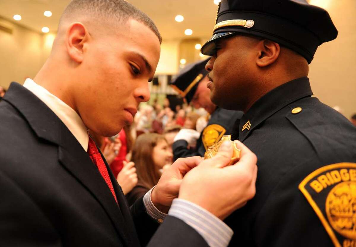 Seventeen-year-old Jordan Grice pins a sergeant's badge on his father Jeffery Grice during Bridgeport's Sergeant Promotional Ceremony Wednesday Feb. 3