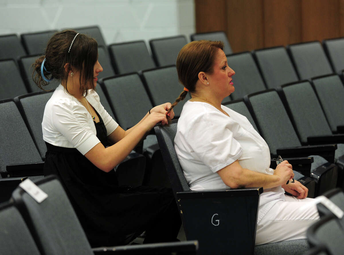 Graduate Stephanie Smith gets her hair braided into a ponytail by her daughter Abby, 11, before the start of the Porter and Chester Institute's Pinning and Candle Lighting Ceremony for its first ever graduating class of nurses from its Stratford campus at Bunnell High School in Stratford, Conn. on Thursday January 23, 2014.