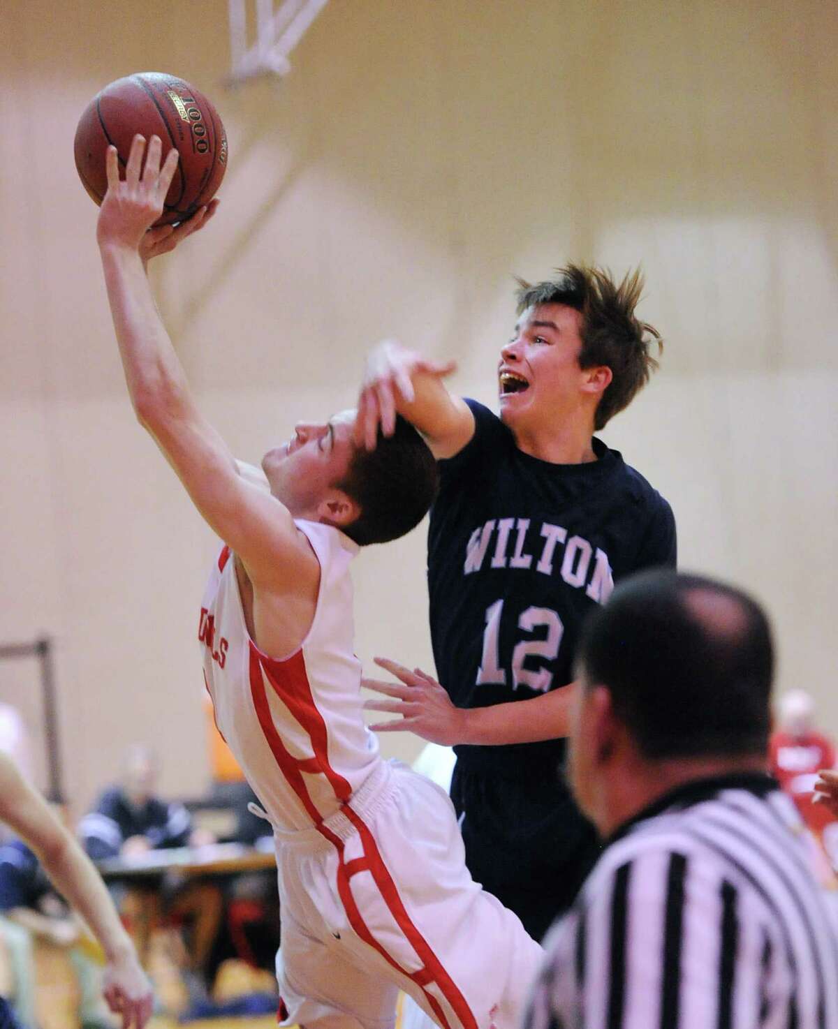 At left, Patrick Santini of Greenwich gets past Richie Williams (#12) of Wilton to score on a driving layup during the boys high school basketball game between Greenwich High School and Wilton High School at Greenwich, Firday night, Jan. 24, 2014.
