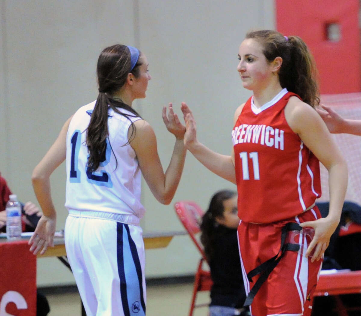 At left, Haley English (#12) of Wilton high-fives Alexa Moses (#11) of Greenwich at the conclusion of the girls high school basketball game between Greenwich High School and Wilton High School at Greenwich, Friday, Jan. 24, 2014. Wilton defeated Greenwich, 49-40.