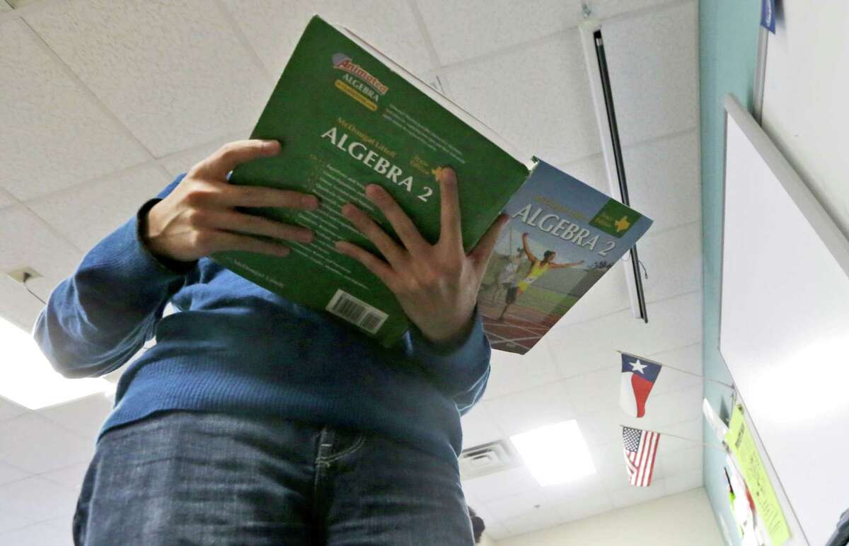 In a Wednesday, Jan. 15, 2014 photo, a high school student holds an open algebra II book in math class at Flower Mound High School in Flower Mound, Texas, Wednesday, Jan. 15, 2014. Texas became the first state to require its high school students to take algebra II, betting tougher graduation standards would better prepare its youngsters for college and life beyond it. Since then, 16 other states and the District of Columbia have followed suit, and two more will by 2020. But Texas is now bucking the trend it began, abandoning advanced-math mandates to give high school students more flexibility to focus on vocational training for jobs that pay top dollar but don’t necessarily require a college degree. (AP Photo/LM Otero)