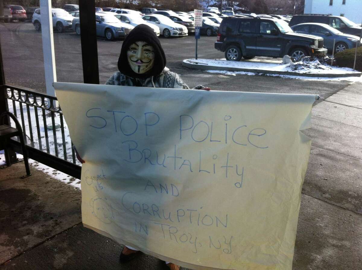 An anonymous protester holds up a sign outside Troy City Hall to decry police brutality. (Kenneth C. Crowe II / Times Union)