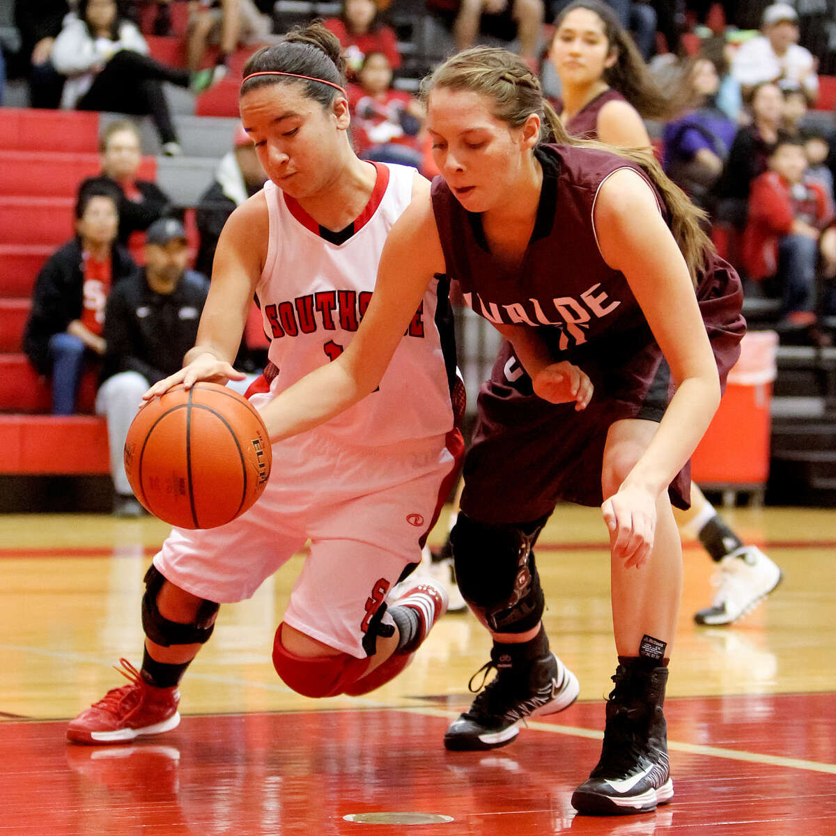 Southside's Sabrina Guzman, left, fights for the ball with Uvalde's Brittany Sendejo during the first quarter of their game at Southside High School on Saturday. The Lady Cardinals beat Uvalde 62-44, which, along with a Harlandale loss, moved Southside into third place in district play.