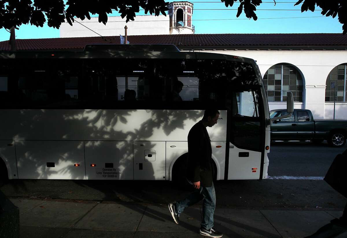 Pedestrians walk by as a so-called "Google Bus" pulls away Friday morning Jan. 24, 2014 on 18th Street and Church Street in the Mission District in San Francisco.