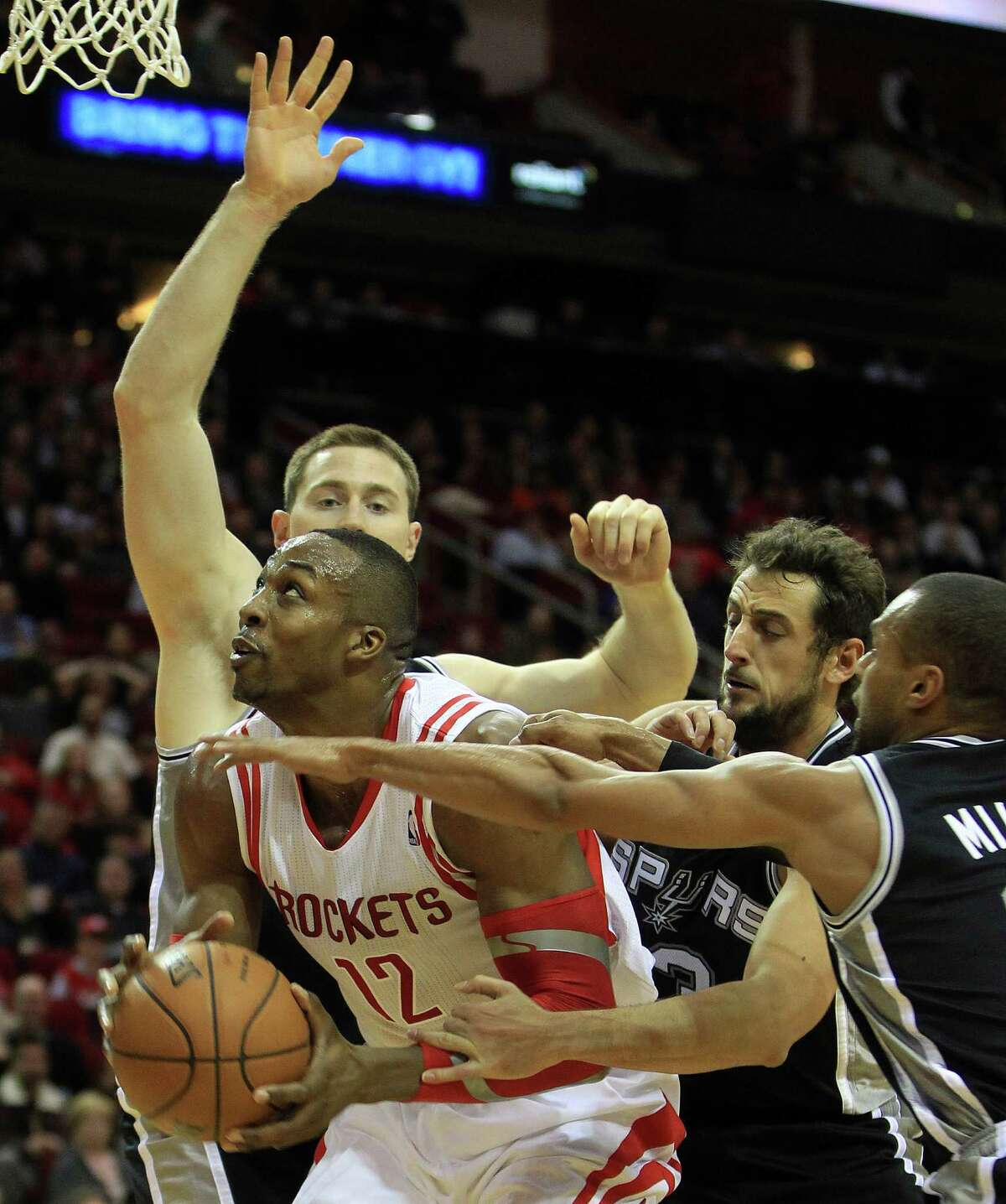 Houston Rockets center Dwight Howard (12) fights to get to the basket against San Antonio Spurs power forward Aron Baynes (16), Marco Belinelli (3) and Patty Mills (8) during the second half of an NBA game at Toyota Center,Tuesday, Jan. 28, 2014. Rockets beat the Spurs 97-90.