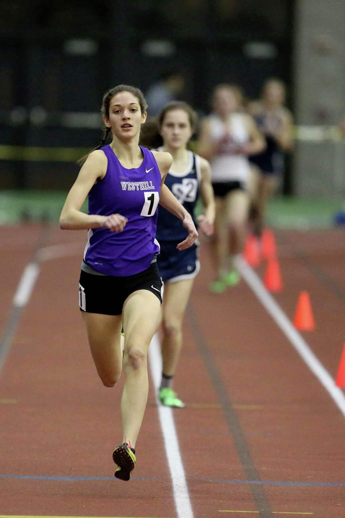 Westhill High School's Claire Howlett takes the lead down the stretch over Staples High School's Hannah DeBalsi during Wednesday evening FCIAC Track Championships in New Haven. Howlett would win the 1600 meter heat.
