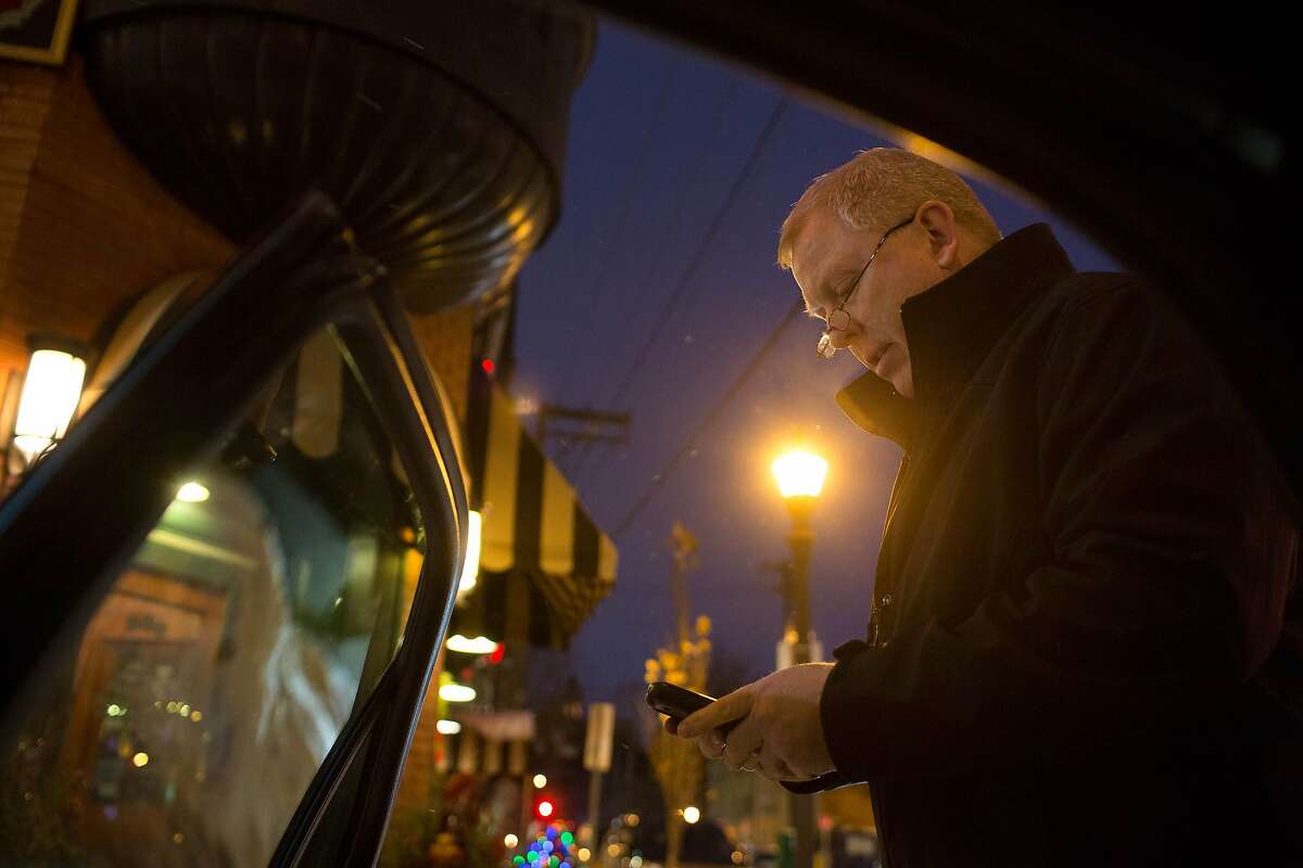 In this Dec. 20, 2013 photo, Jon Sasseville, a driver for UberX, texts a customer to say that he has arrived in St. Paul, Minn. Uber has an app for smartphones that connects drivers with people who want rides. It is the best known of a new generation of car services. (AP Photo/Minnesota Public Radio, Jennifer Simonson)