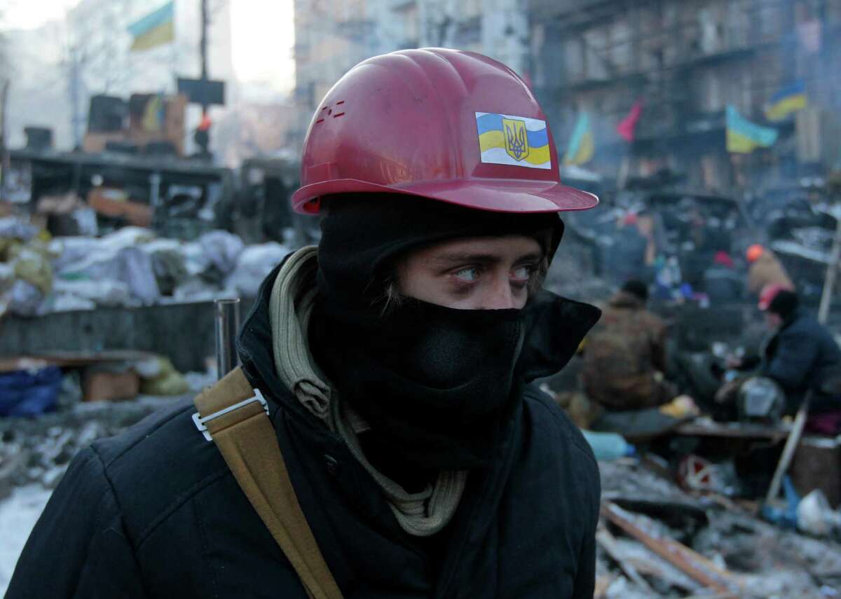 An opposition supporter looks at barricade in central Kiev, Ukraine, Thursday, Jan. 30, 2014. Ukraine's embattled President Viktor Yanukovych is taking sick leave, his office announced Thursday, leaving it unclear how involved he may be in efforts to resolve the country's political crisis in which protesters are calling for his resignation. (AP Photo/Sergei Chuzavkov)