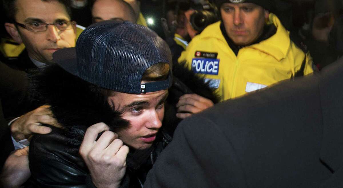 Canadian musician Justin Bieber is swarmed by media and police officers as he turns himself in in Toronto.