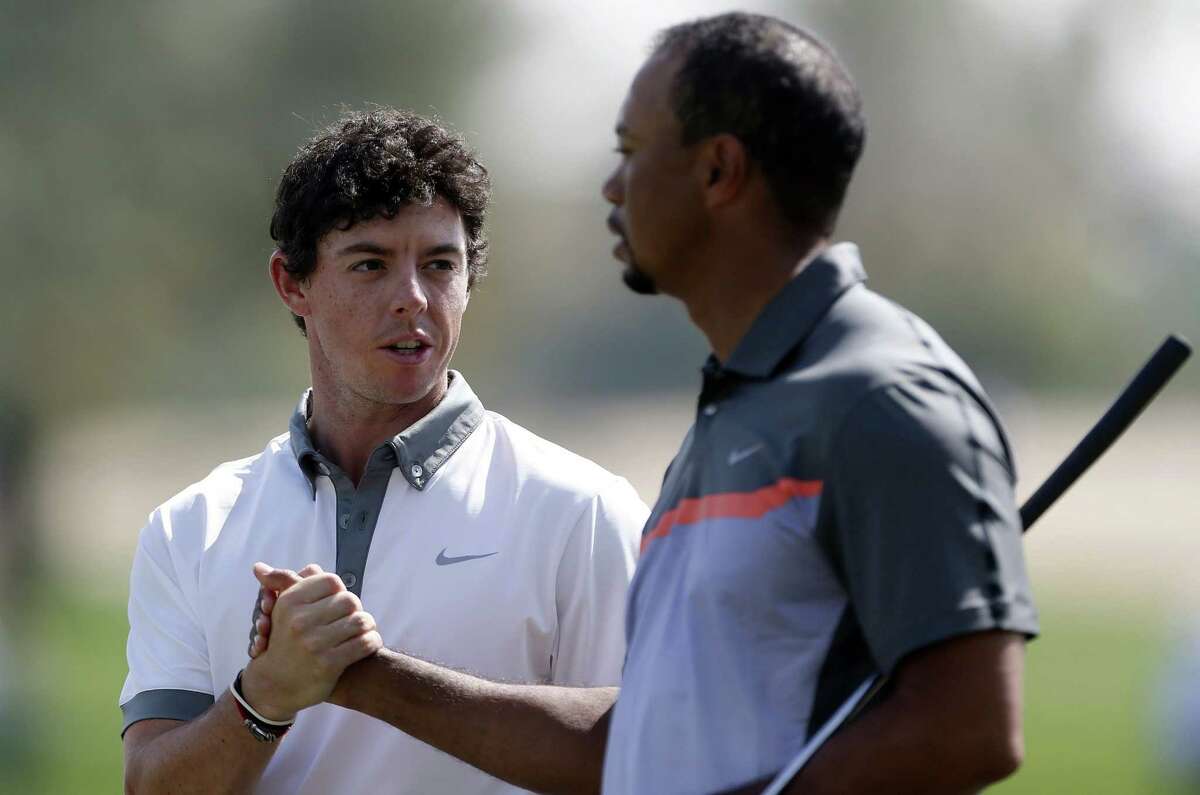 Rory McIlroy (left) and Tiger Woods shake hands during the first round of the Dubai Desert Classic. McIlroy took the lead with a 63, while Woods was five shots behind with a 68.