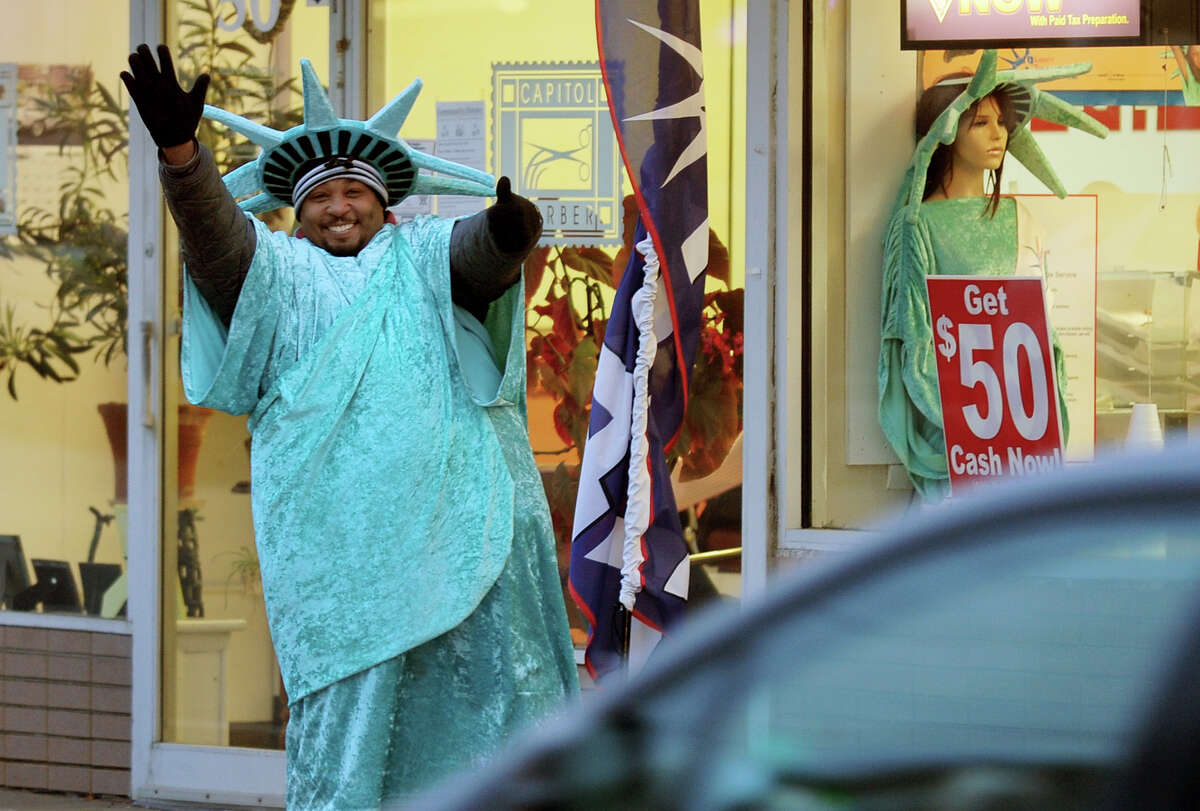 Qushoun Washington, who works for Liberty Tax Services, waves to cars as they pass by on Bridge Street in downtown Ansonia, Conn. on Friday January 31, 2014.
