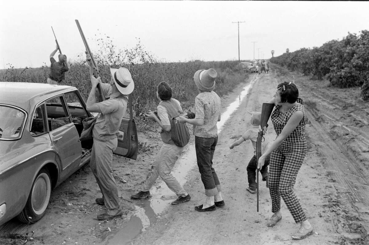 Members of the Thrash and Burns families, and their friends hunt white-winged doves along a muddy, dirt road, Giddings, Texas, 1961.