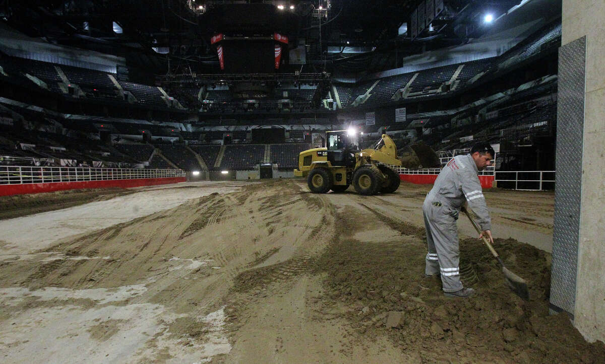 Miguel Ramirez, (right) an employee of Unison Drilling, spreads dirt Monday February 3, 2014 on the floor of the AT&T Center. The AT&T Center is undergoing the traditional conversion from the home of the Spurs to the home of the San Antonio Stock Show & Rodeo. The arena requires 2,160 tons of soil and takes 70 truckloads to move the soil from its storage location to the AT&T Center.