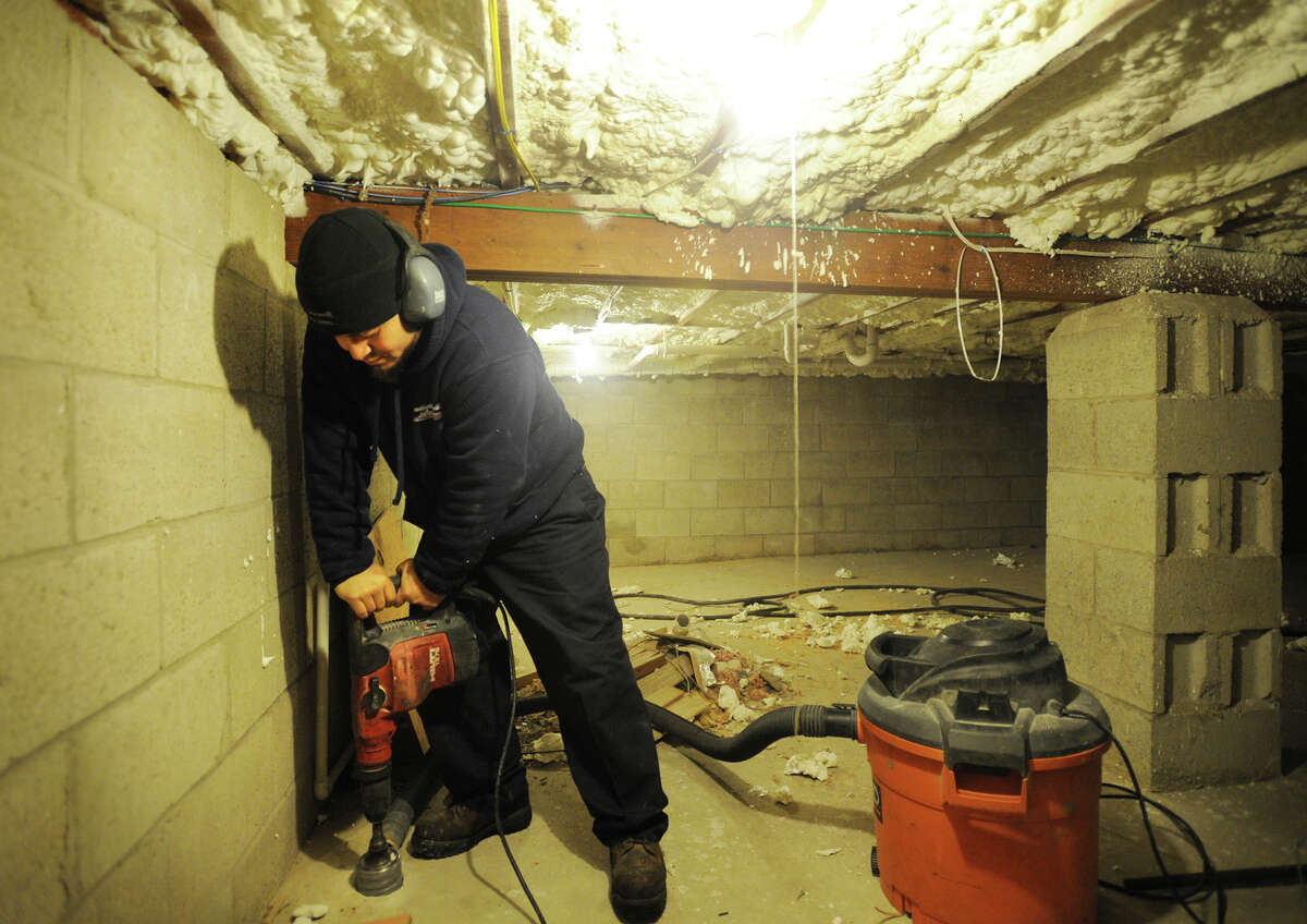 Ralph Colon, of Connecticut Basement Systems Radon, Inc. in Stratford, drills a hole through a crawlspace slab as part of a radon remediation job in Wilton, Conn. on Tuesday, February 4, 2014.