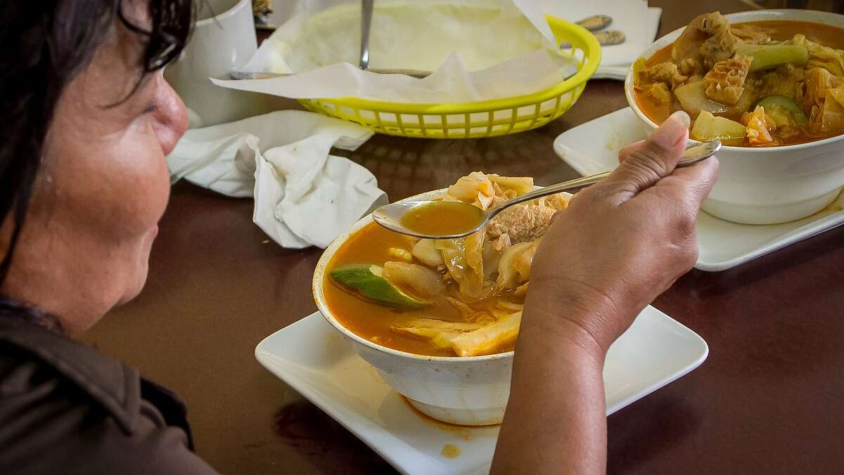 A woman enjoys the Sopa de Pata, Beef Tripe and Feet soup at Reina's restaurant in San Francisco, Calif., on February 4th, 2014.