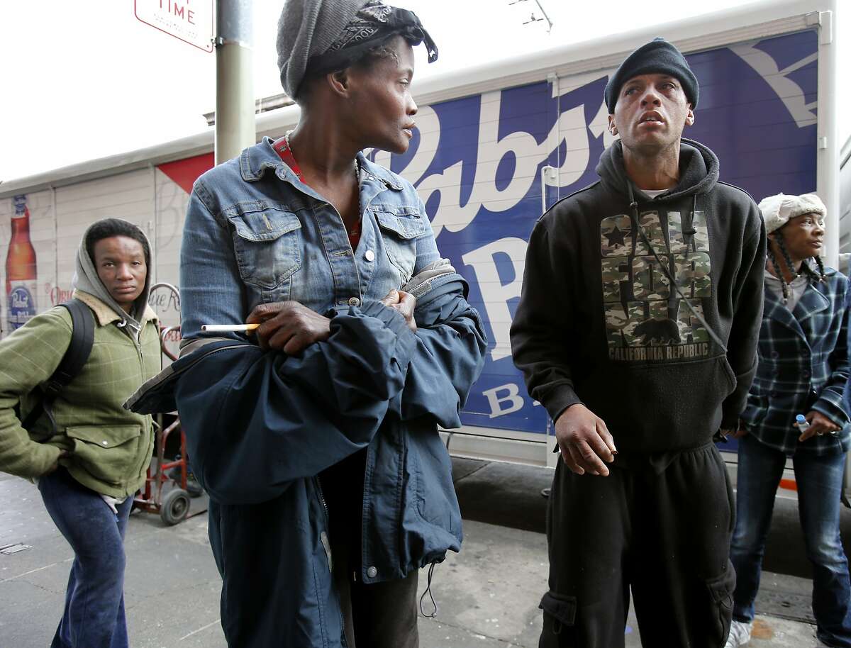 A group of people gather behind a large liquor delivery truck as it stops on Turk Street Tuesday February 4, 2014 in San Francisco, Calif. Community and homeless organizers have gotten "no parking" signs along the first block of Turk Street, an area with a longtime drug problem. They say that parked cars and trucks provide cover for illegal activities on the block.