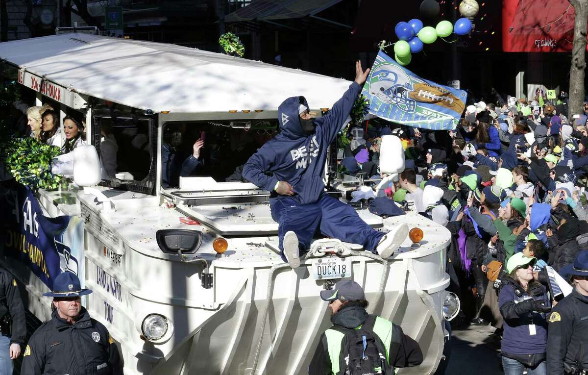 Seahawks running back Marshawn Lynch throws candy into the crowd while riding on the hood of an amphibious vehicle during the team's championship parade through Seattle. Police estimated about 700,000 people attended the city's celebration.