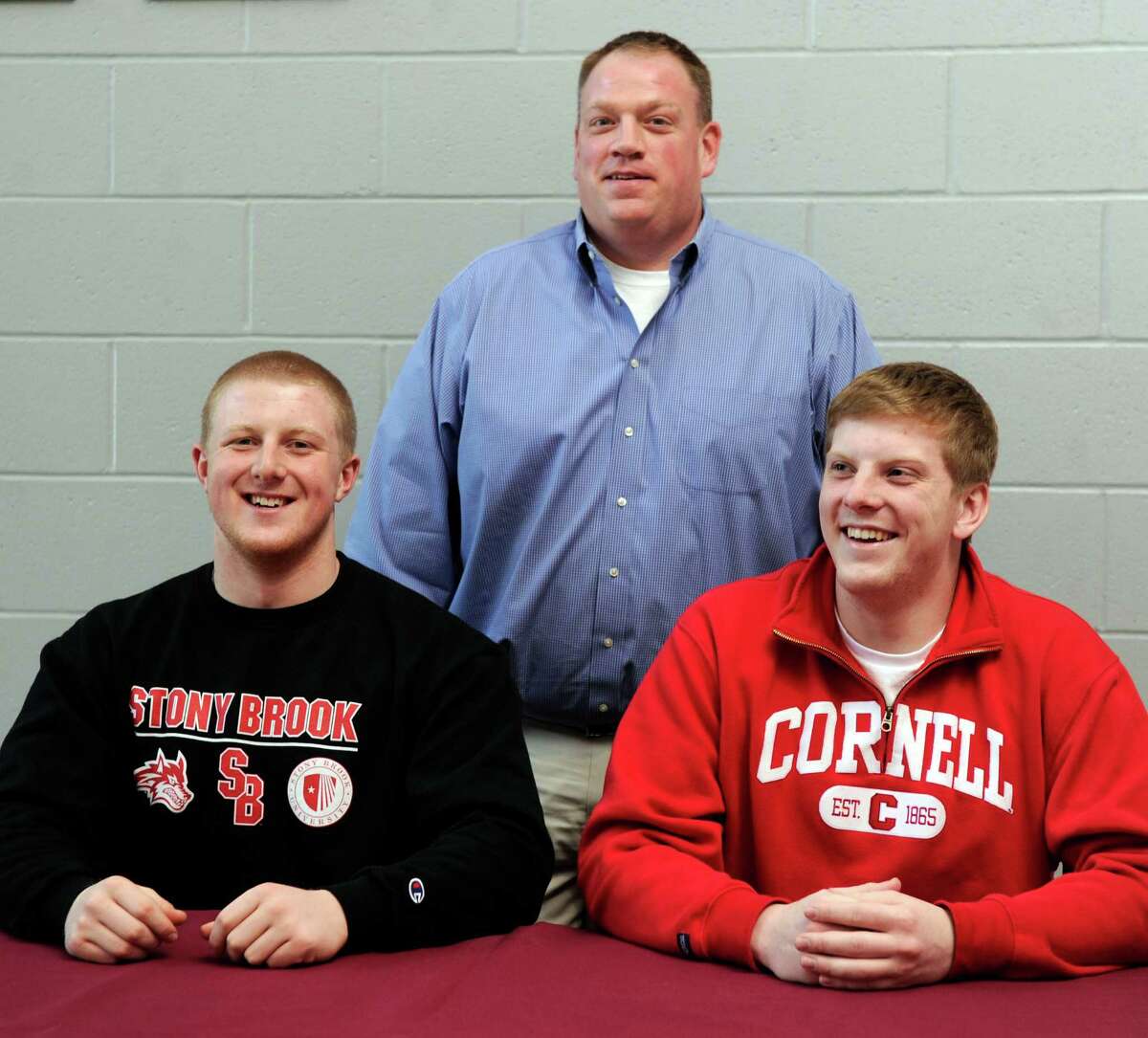 Bethel High School Football Coach Jason Gill stands with Calvin Daniels, 18, left, and Ian Melvin, 17, at the high school Thursday, Feb. 6, 2014. The two students have have committed to playing football in college.