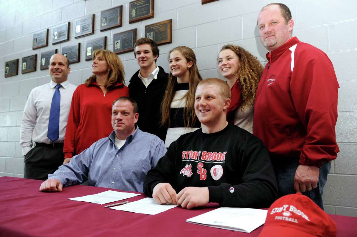 Calvin Daniels, 18, foreground, is photographed with his family and school officials at Bethel High school Thursday, Feb. 6, 2014, in a signing ceremony declaring his intention to play football in college.