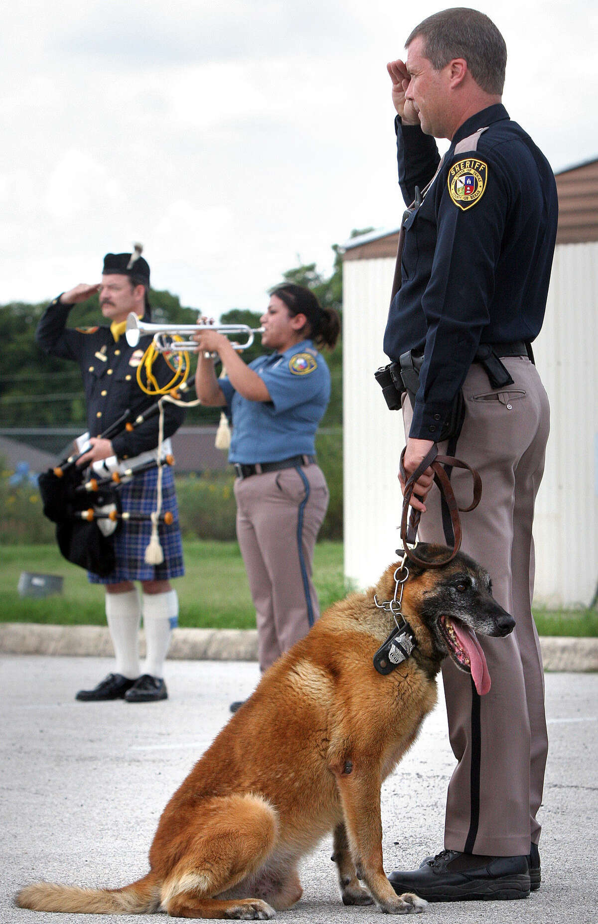 Deputy Steve Benoy (right) of the Bexar County Sheriff K9 Unit is shown at a police dog's 2007 memorial service. He now has been indicted for the heat exhaustion deaths of two police dogs after allegedly leaving them in a hot patrol vehicle overnight.