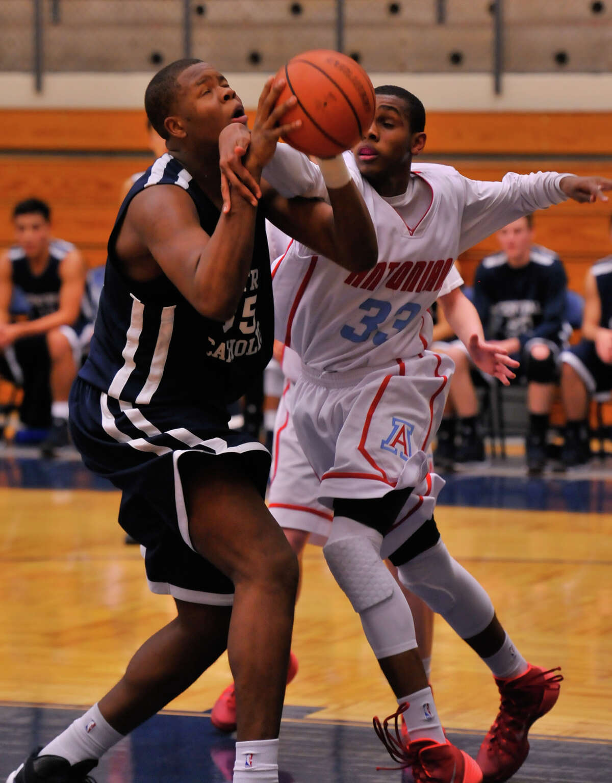 Central Catholic's Tony Lewis (left) is fouled by Antonian's Jamel Bradley during their Feb. 6, 2014 game. The Buttons won 66-55.