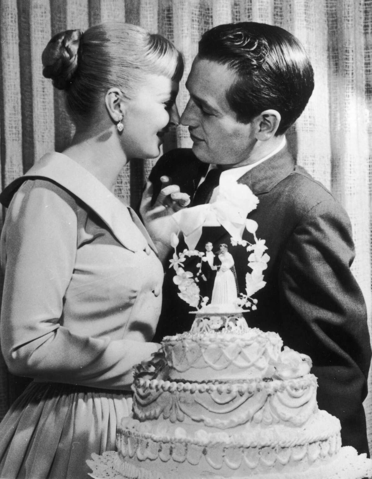 American actors and newlyweds Paul Newman and Joanne Woodward kiss behind a wedding cake during their wedding reception at the El Rancho hotel-casino, Las Vegas, Nevada, January 29, 1958.