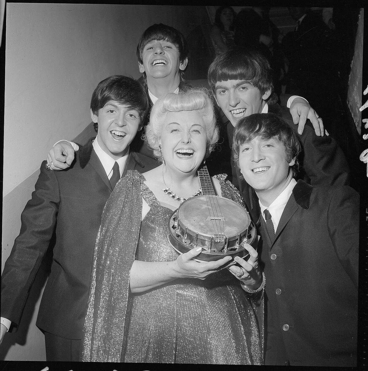 The Beatles take a break backstage with singer and banjo player Tessie O'Shea who is probably best known for the song "Two Ton Tessie from Tennessee," despite being Welsh.
