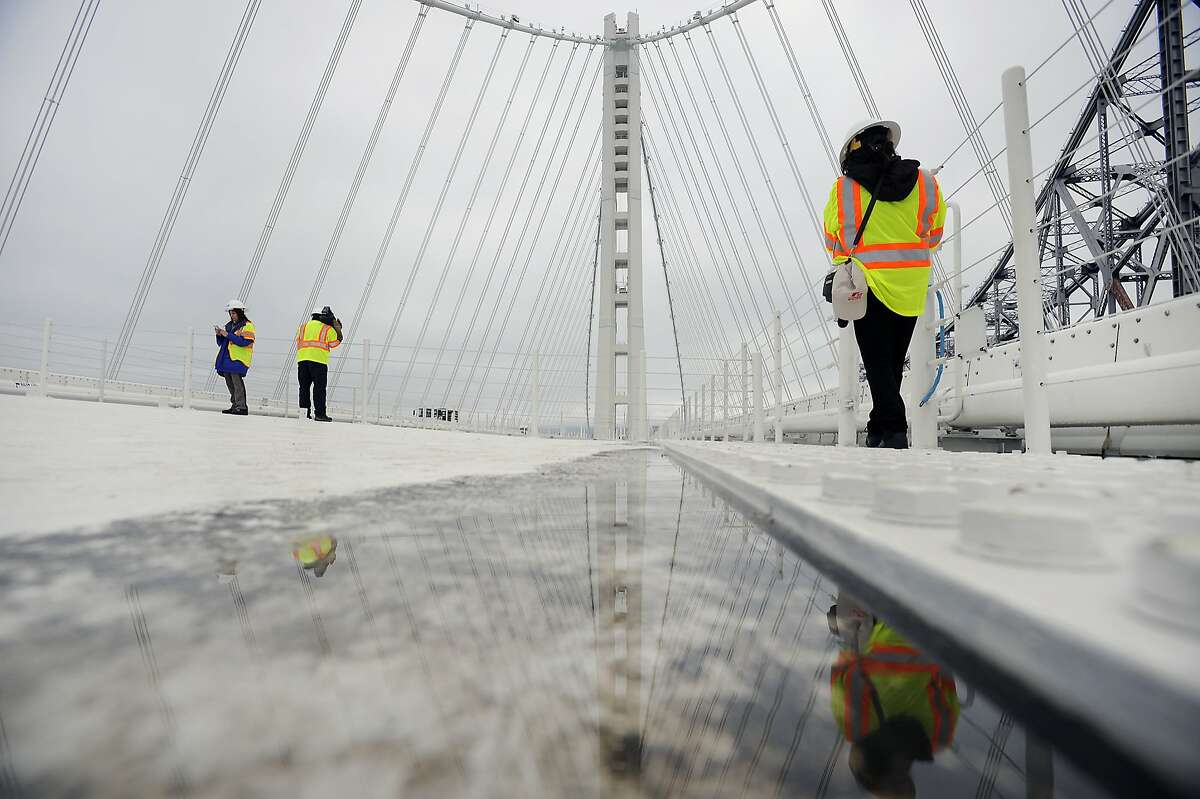 Members of the media are seen on top of the Eastern span of the Bay Bridge during a tour to see the newly discovered leaks in the roadway, in Oakland, CA Monday, February 10, 2014.
