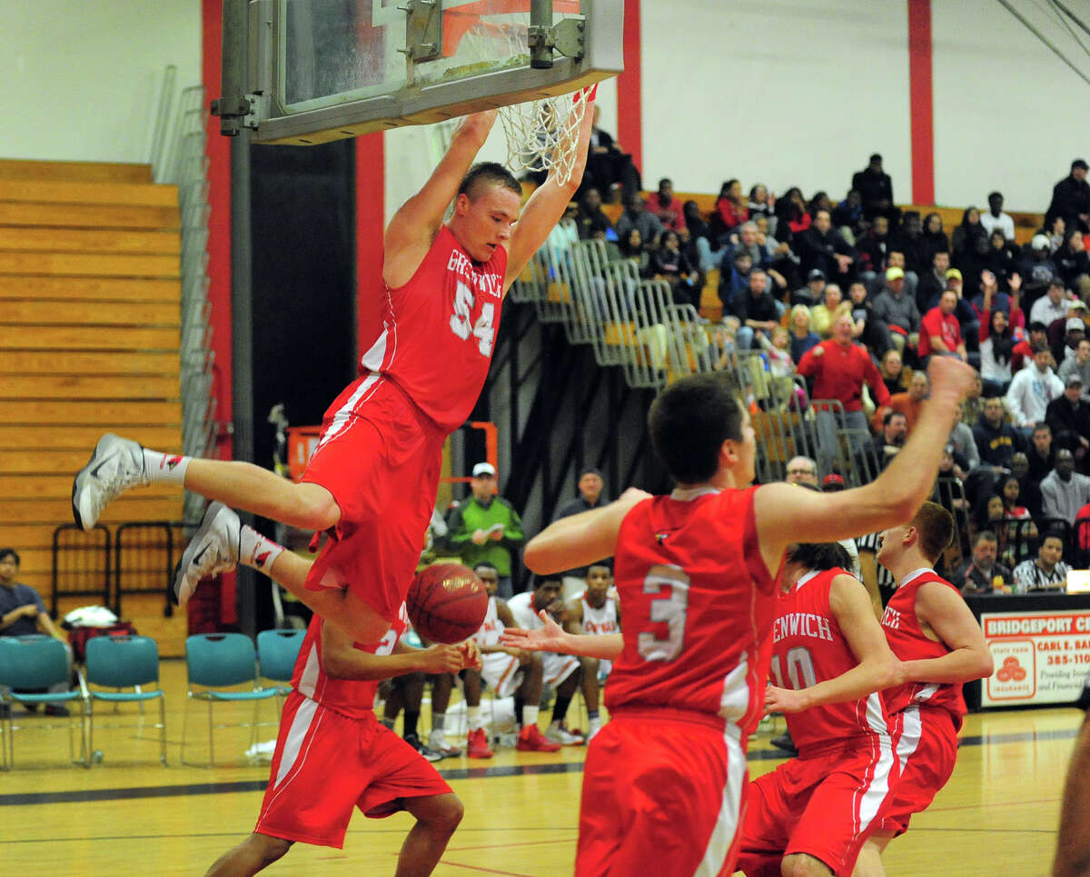 Greenwich's Alex Wolf hangs onto the rim after a slam dunk, during boys basketball action against Central in Bridgeport, Conn. on Tuesday February 11, 2014.