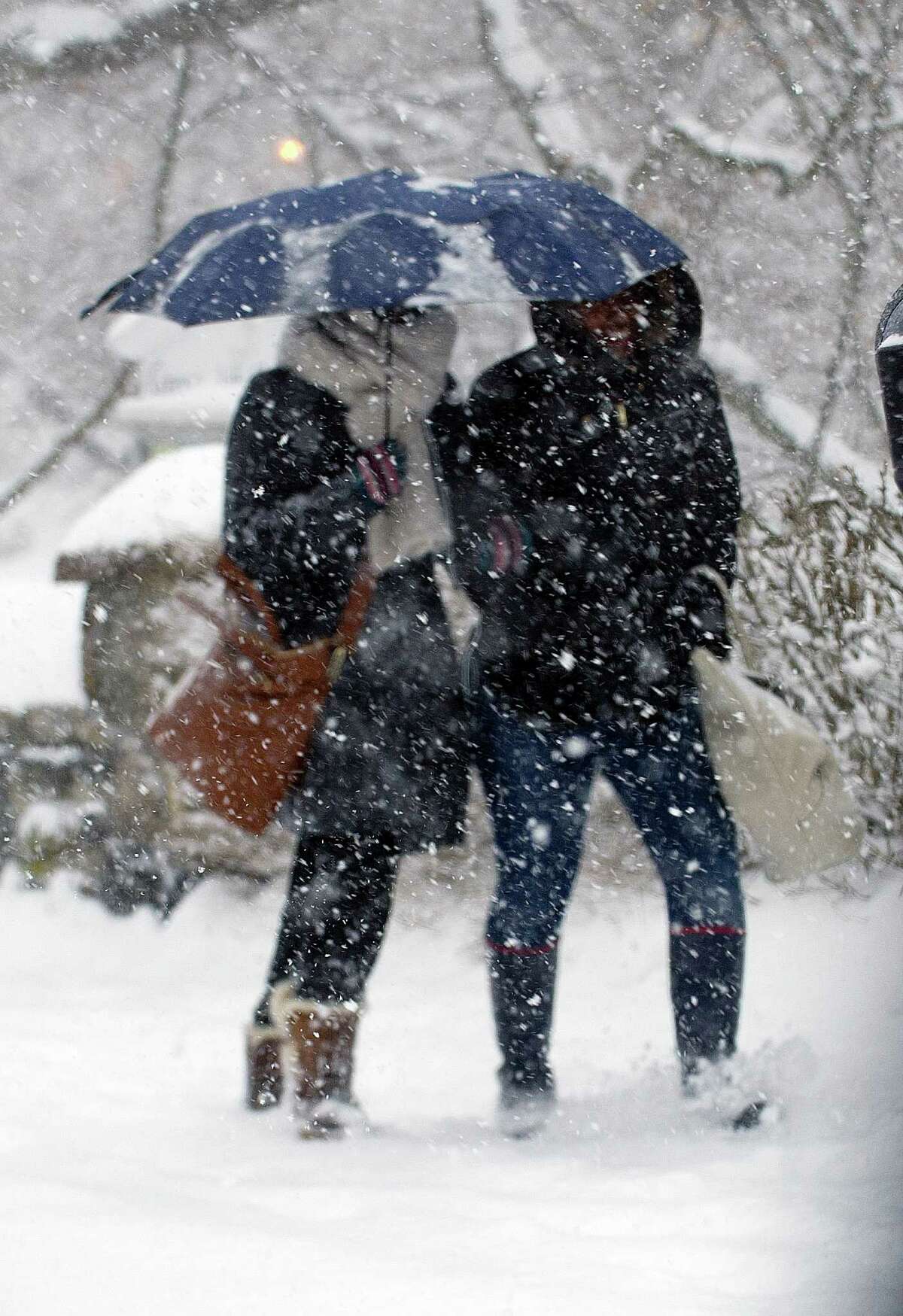 Tyiesha Collins, left, and Ashley Richardson, right, share an umbrella as they walks through the snow in Greenwich, Conn., on Thursday, February 13, 2014. The two were walking to their jobs at Zara, where they said they would call the corporate office to see if they were to be open or closed. The snow made Richardson's commute extra difficult because she came into Greenwich from Bridgeport. "For me it's a super super pain to get here and then they're like, 'Okay, you're closed, you can go home,'" she said.