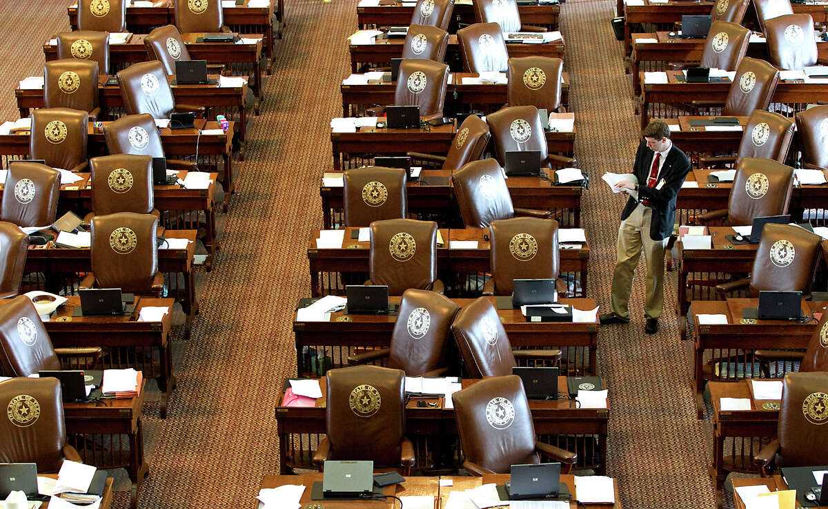 A member of the Sergeant at Arms, Jack Adams, places updated resolutions on the empty desks of House Representatives at the State Capitol on Sunday, May 26, 2013, in Austin, Texas. Members of the House of Representatives left the chamber to gather in their respective caucuses before returning to continue the 83rd Legislature. (AP Photo/Austin American-Statesman, Rodolfo Gonzalez)