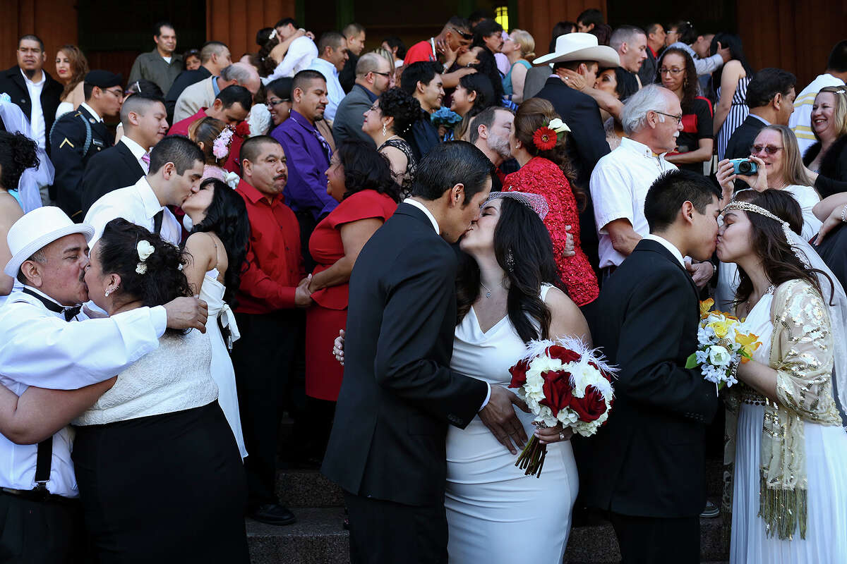Couples including Oscar Palacios with Matilde Martinez, from left, Anthony Sanchez with Stephanie Hernandez, and Analicia Vazquez with John Vazquez, kiss after saying their vows during a mass wedding on the steps of the Bexar County Courthouse in San Antonio on Friday, Feb. 14, 2014.