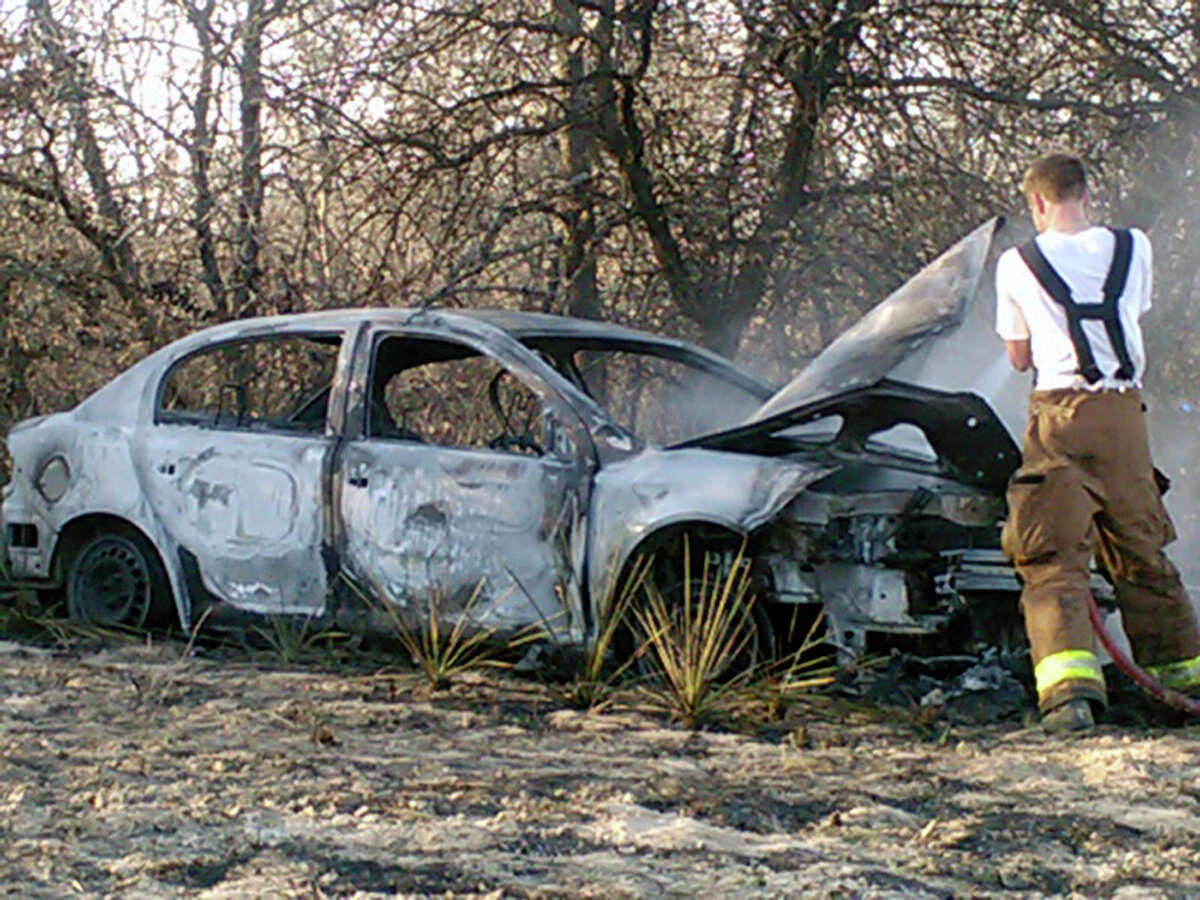 Harmony Volunteer Fire Department firefighter Preston Welch inspects the shell of a car at the scene of a brush fire on Saturday afternoon. Crews from four area fire departments battled the brush fire on the far Southeast Side after the wrecked car burst into flames. It was unclear what happened to the driver or how many passengers were involved, if any. At least one woman suffered from smoke inhalation, but no other injuries were reported.