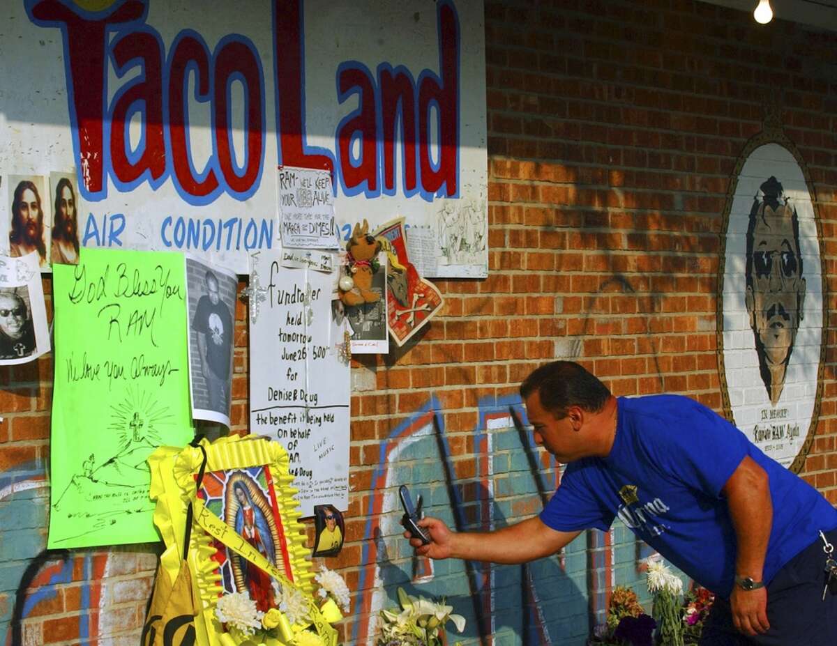 Richard Hodge uses his cell phone to take pictures of a memorial for Ramiro "Ram" Ayala on June 26, 2005.
