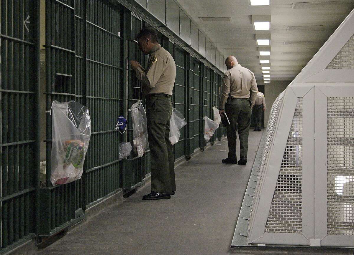 FILE - In this Oct. 3, 2012, file photo, Los Angeles County Sheriff's deputies inspect a cell block at the Men's Central Jail in downtown Los Angeles. A new federal civil rights indictment alleges that two Los Angeles County sheriff's deputies beat a handcuffed prisoner at the Men's Central Jail. The four-count indictment returned by a grand jury late Thursday Feb. 6, 2014, follows earlier indictments of 18 current and former Los Angeles County deputies on corruption and civil rights offenses. (AP Photo/Reed Saxon, File)