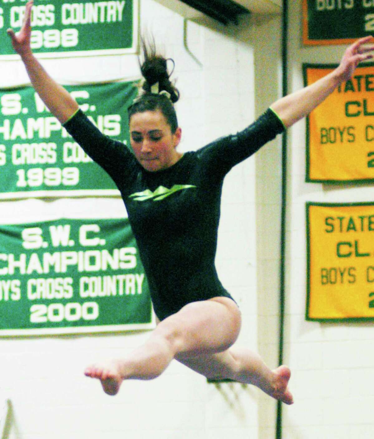 Alison Profeta of the Green Wave soars above the balance beam Feb. 20, 2014 at New Milford High School en route to capturing the South-West Conference gymnastics all-around individual title. Coach Bethany Mihaly's NMHS squad also won the team championship.