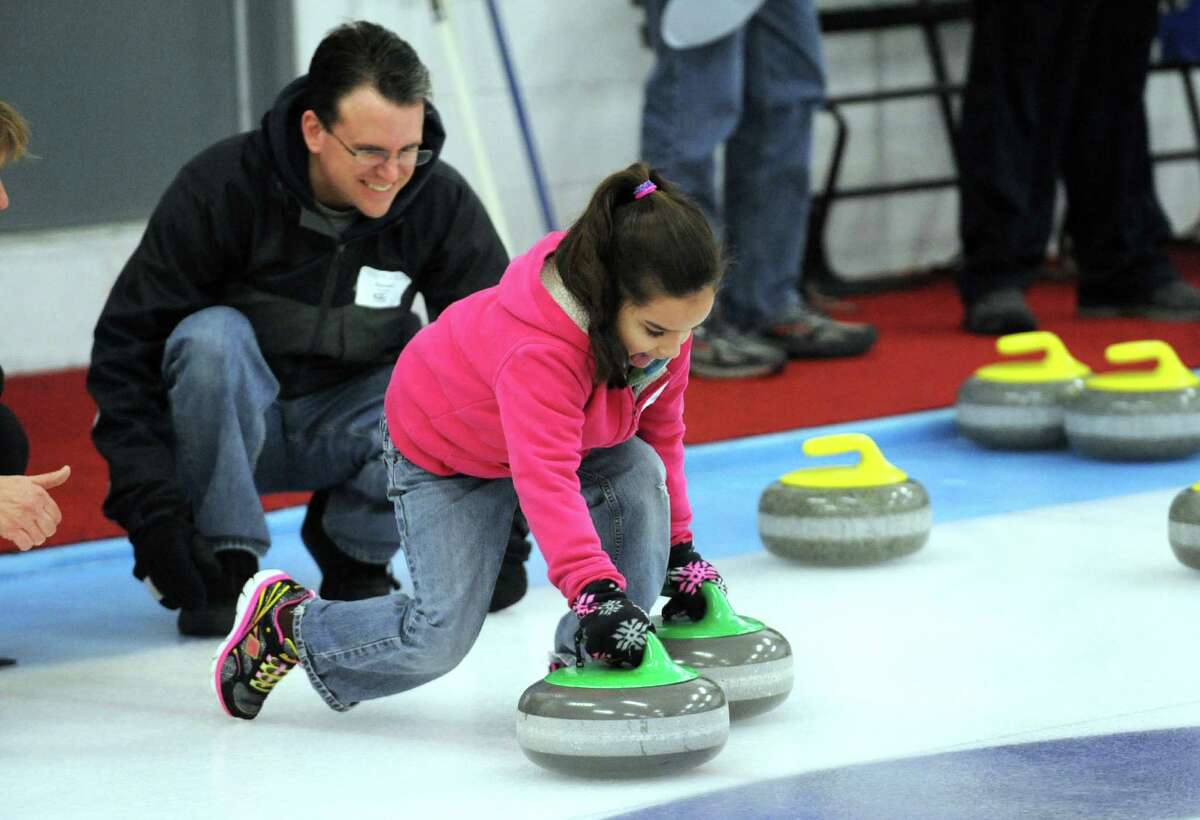 Seven-year-old Marisil Van Slyke is watched by her dad, Chip Van Slyke, of Glenville as she gets an introduction to curling during the Schenectady Curling Club open house on Saturday Feb. 22, 2014 in Niskayuna, N.Y. (Michael P. Farrell/Times Union)