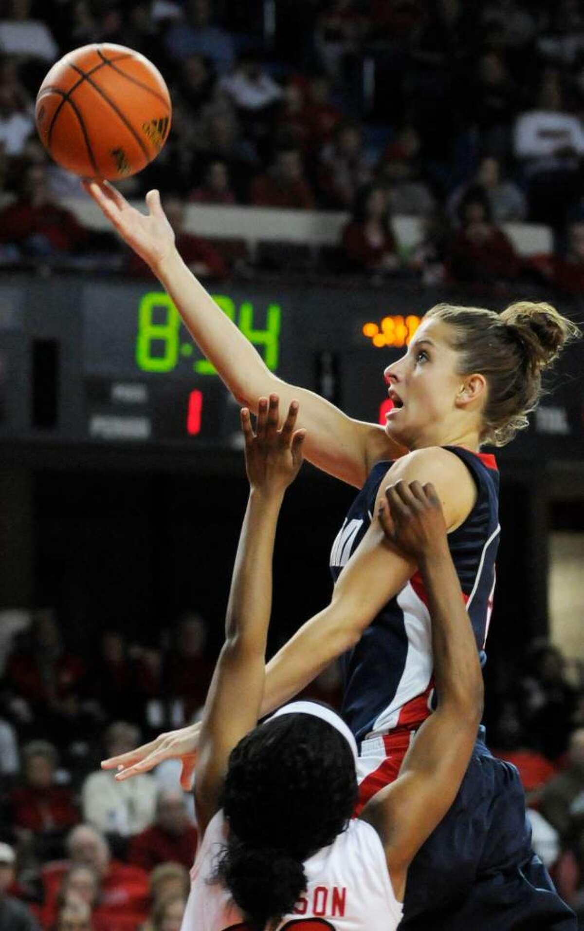 Connecticut's Caroline Doty, top, drives past the defense of Louisville's LaToya Johnson for a layup during the first half of their NCAA college basketball game Sunday, Feb. 7, 2010, in Louisville, Ky. Connecticut defeated Louisville 84-38. (AP Photo/Timothy D. Easley)