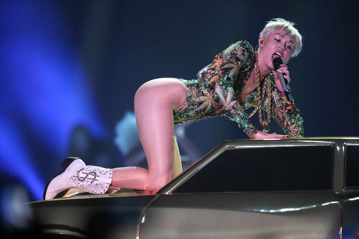 Miley Cyrus performs on top of a car during her show in Oakland.