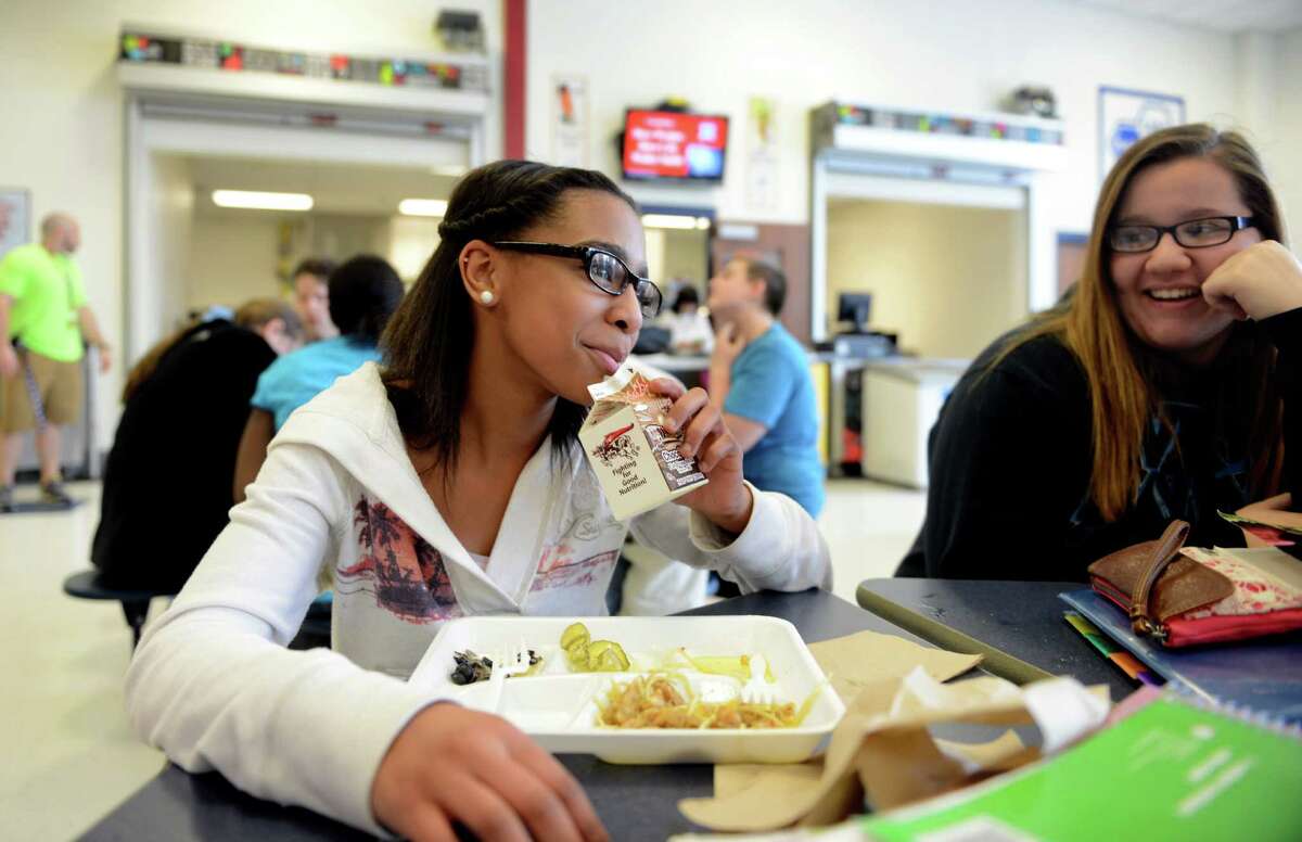 Eighth grade student Nadia Jackson sips on chocolate milk during lunch with Anita Wlazlo, right, Wednesday, Feb. 26, 2014, at Derby Middle School in Derby, Conn. This week, a new study showed that, between 2003-2004 and 2011-2012, obesity rates among children aged 2 to 5 fell about 40 percent. Some experts have credited the drop to the increased attention nationwide to proper nutrition and physical activity.