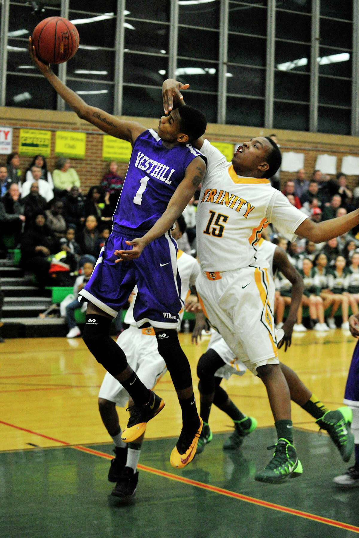 Westhill's Jeremiah Livingston attempts to lay the ball in with Trinity Catholic's Tyrell St. John's hand in his face during their game at Trinity Catholic High School in Stamford, Conn., on Wednesday, Feb. 26, 2014. Westhill won, 67-63.