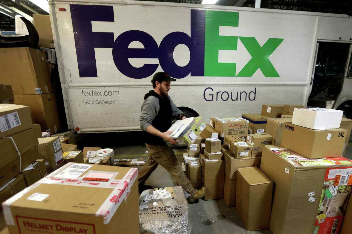 FILE - In this Dec. 16, 2013 file photo, package handler Chris Addison arranges packages before loading a delivery truck at a FedEx sorting facility in Kansas City, Mo. Santa's sleigh didn't make it in time for Christmas for some this year due to shipping problems at UPS and FedEx.The delays were blamed on poor weather earlier this week in parts of the country as well as overloaded systems. (AP Photo/Charlie Riedel) ORG XMIT: NY116