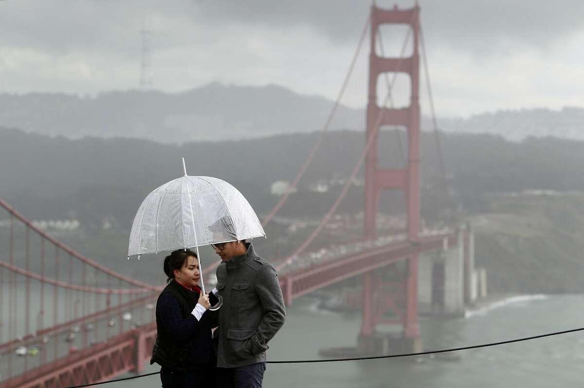 Visiting from Las Vegas, Gee Olivar (left) and her boyfriend Dax Timbol stop at the Marin Headlands in the rain on Friday, Feb. 28, 2014. Stormy weather continues to drench the Bay Area, but will hardly make a dent in the drought conditions.