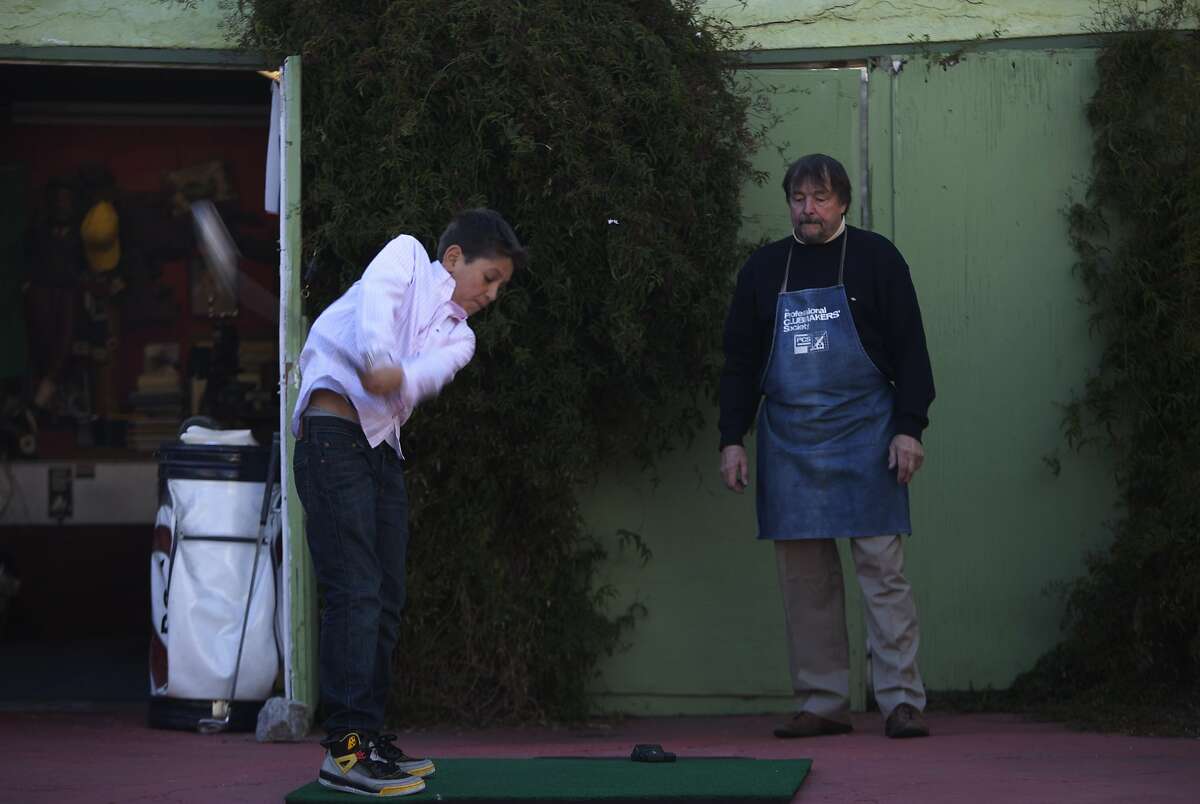 Michael Lee Clark shows how he measures the club head speed that his son Kostia, 12 years old, swings on a patch of green using a swing meter in front of his garage in Berkeley, Calif., on Monday, January 20, 2014.