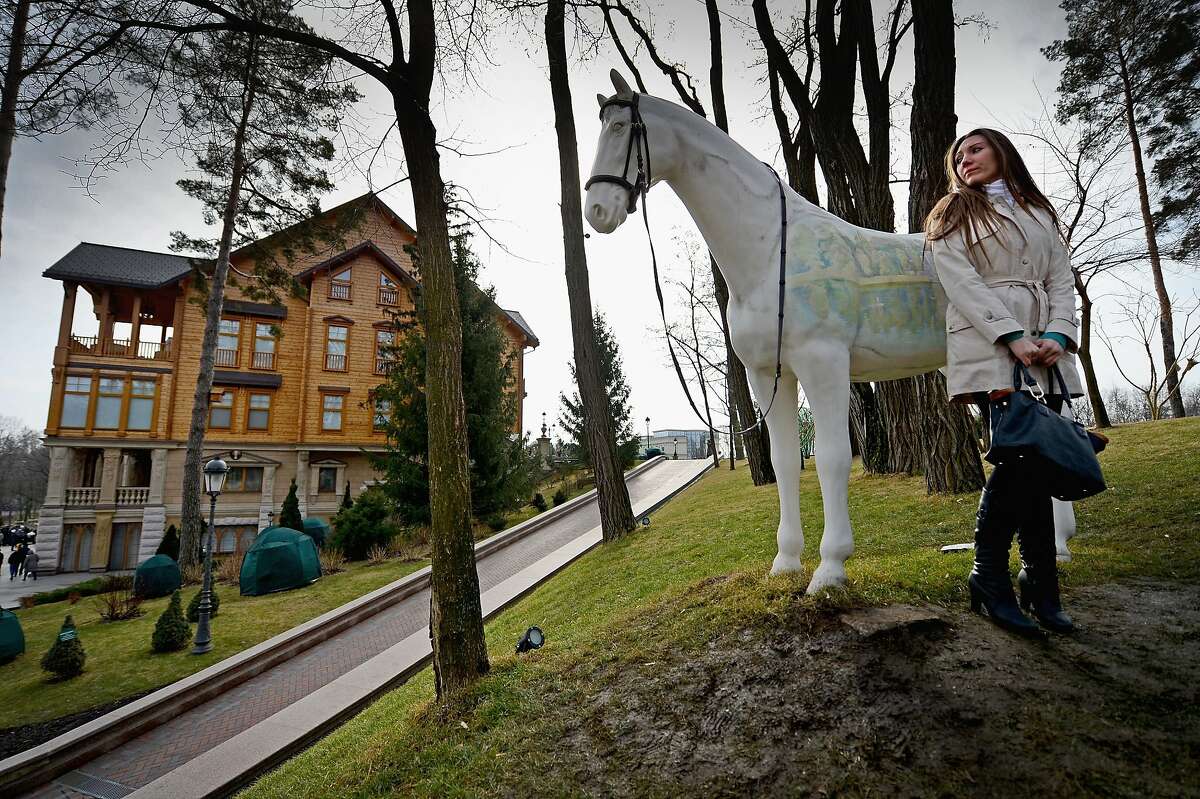 A woman stands near a sculpture of a horse around President Viktor Yanukovych's Mezhyhirya estate, which was abandoned by security in Kiev, Ukraine. Citizens of the country were able to view first-hand the excesses of their former President.