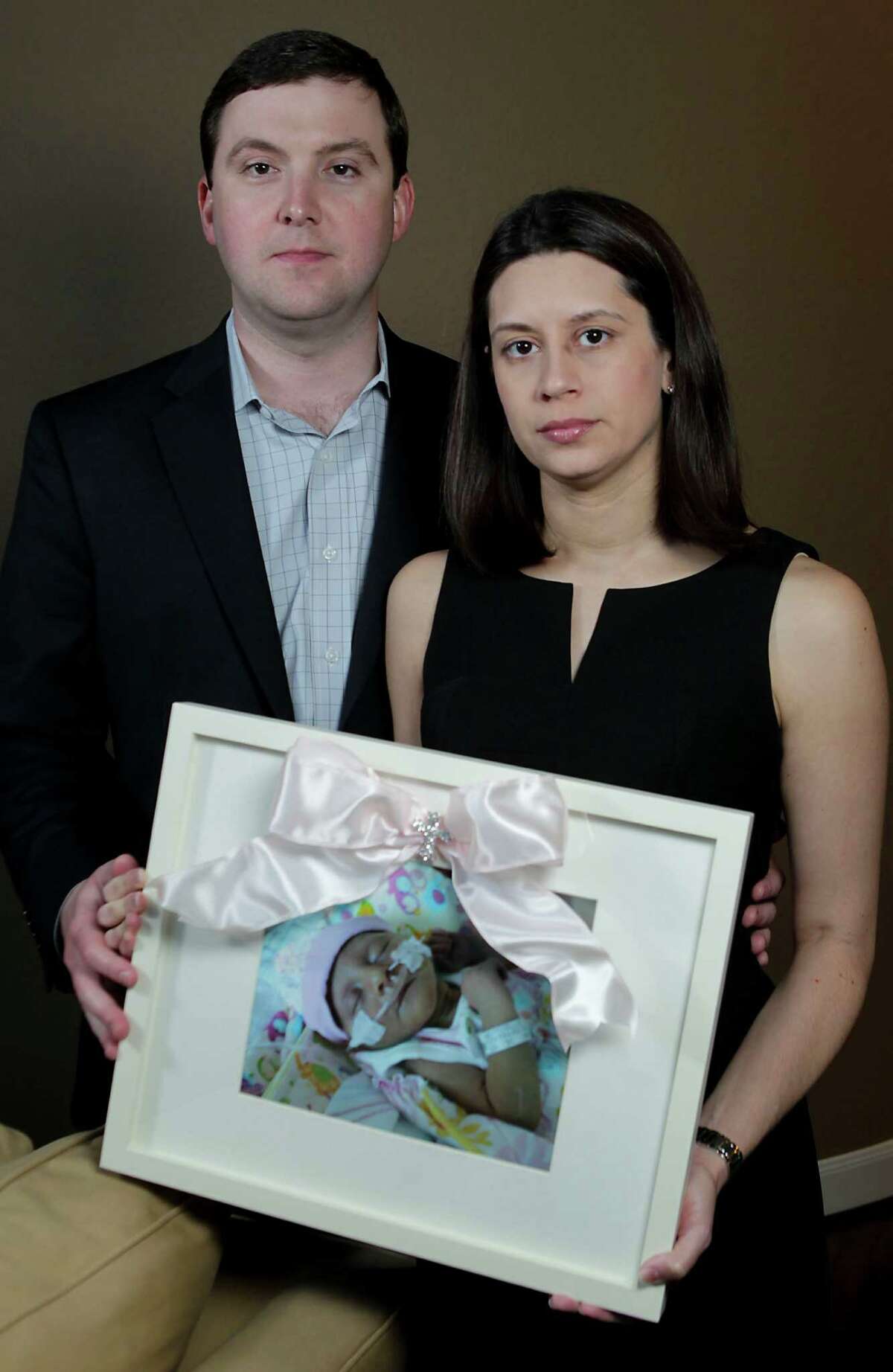 Farah and Patrick Armstrong of Katy hold a picure of their daughter Madeline Leigh Armstrong, who died of CMV, a rare viral infection.