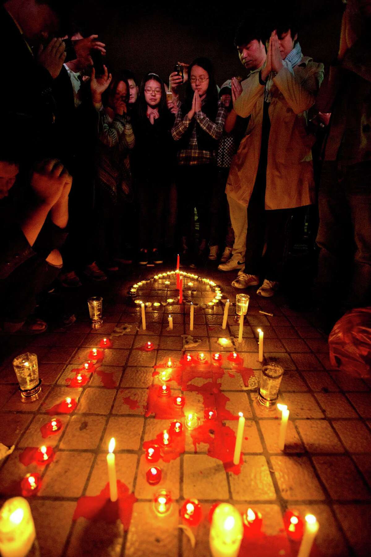 People light up candles and pray for the victims on a square outside the Kunming Railway Station where more than 10 assailants slashed scores of people with knives the night before in Kunming, in western China's Yunnan province, Sunday, March 2, 2014. Officials said the attack was a terrorist assault by ethnic separatists from the far west. (AP Photo/Alexander F. Yuan)